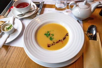 Fish soup, cup of tea,teapot,spoon,bred, butter,glass of water on restaurant table