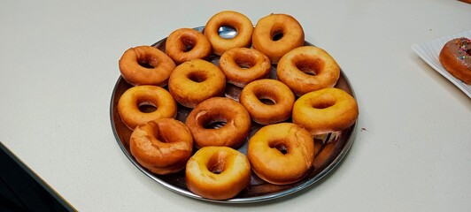 assorted donuts with chocolate frosted, pink glazed and sprinkles donuts. Donuts in hand or tray
