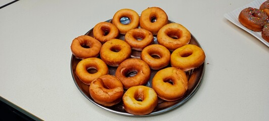 assorted donuts with chocolate frosted, pink glazed and sprinkles donuts. Donuts in hand or tray
