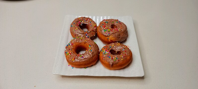 assorted donuts with chocolate frosted, pink glazed and sprinkles donuts. Donuts in hand or tray