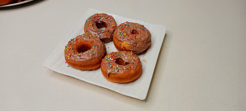 assorted donuts with chocolate frosted, pink glazed and sprinkles donuts. Donuts in hand or tray