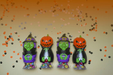 Fototapeta premium Terrible figures of witches and monsters on a light background strewn with colorful confetti. The concept of the terrible Halloween holiday. Festive figurines. Empty space. Halloween days