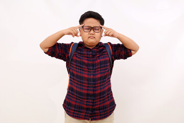 Thoughtful asian school boy standing while pointing his head. Isolated on white background