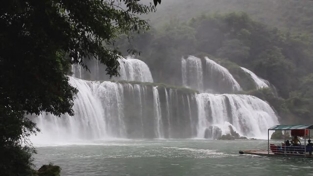 Tourist raft getting close to Ban Gioc waterfall, the largest transborder waterfall in Vietnam and China during a rainy day