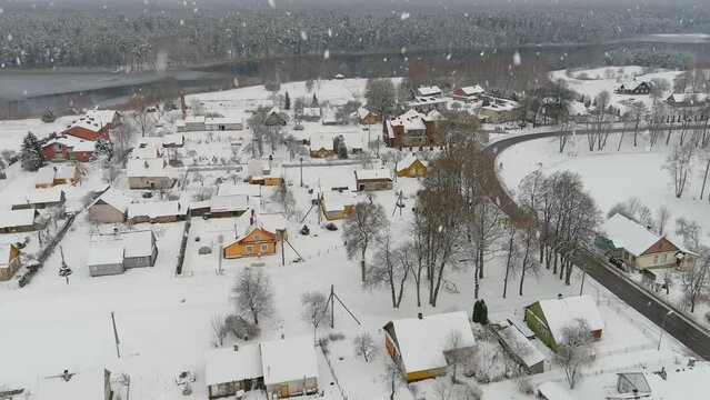 Countryside village rooftops during heavy snowfall, aerial drone view