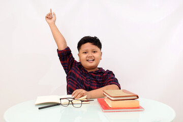 Smart asian school boy raising his hand while studying. Isolated on white background