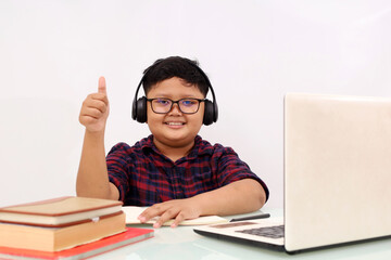 Happy asian school boy studying online using laptop while showing thumbs up. Isolated on white background with copyspace