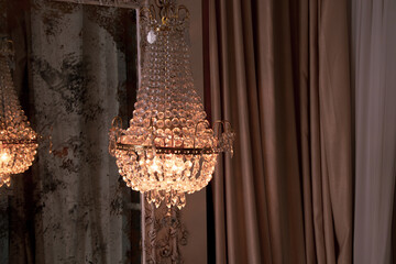 Crystal old chandelier hanging near the mirror at home, vintage interior, vintage chandelier