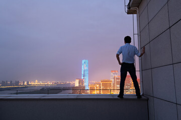 Businessman standing on the rooftop and looking away - Powered by Adobe