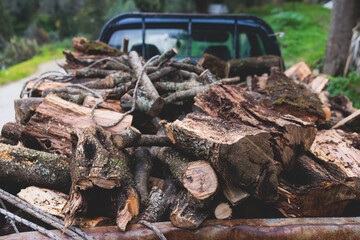 Pickup truck fully loaded with olive tree chopped firewood logs, preparing of woods for fireplace...
