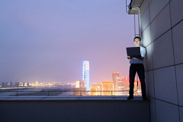 Businessman standing on the rooftop and using laptop