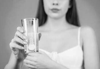 Woman taking drugs to releave headache. Brunette take some pills, holds glass of water, isolated on...