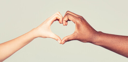 Charity, love and diversity - closeup of female and male hands of different skin color making heart...