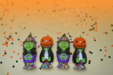 Terrible figures of witches and monsters on a light background strewn with colorful confetti. The concept of the terrible Halloween holiday. Festive figurines. Halloween days