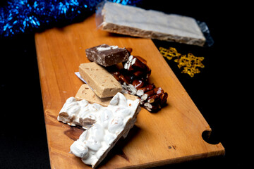 Assortment of nougats on wooden board with black background, traditional sweet in Spain for...