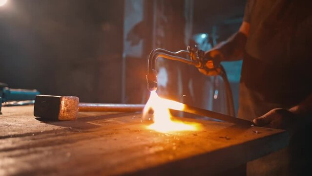 A worker heats steel with an oxygen torch