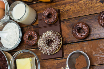 Preparing doughnuts at home. Ingredients for donuts such as eggs, milk, chocolate, pudding, butter, cacao, flour, rolling pin, cake pan, grater, egg beater, spatula
