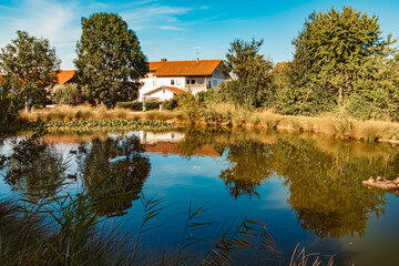 Fototapeta na wymiar Beautiful summer view with reflections in a pond at Aholming, Bavaria, Germany
