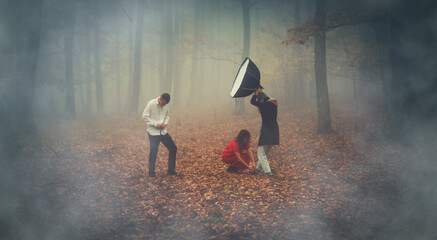 Photographing people in a beautiful foggy forest, the photo also includes an assistant with a...
