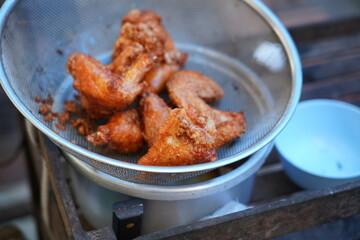 Fried chicken meats which are kept in the grille to release cooking oil and prepare to serve. Food object photo, selective focus.