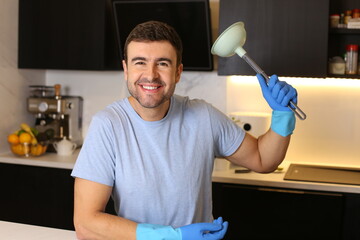 Man holding a plunger in his kitchen 