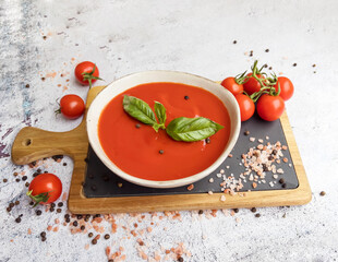 Tomato  soup with basil in a bowl on gray textured background .Gazpacho (gaspacho) cold soup  
