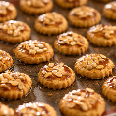 Homemade shortbread dough cookies with caramel and nuts. Festive dessert. Baking is laid out on paper. Close-up, soft focus.