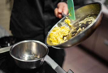 man chef cooking tasty scrambled eggs on kitchen