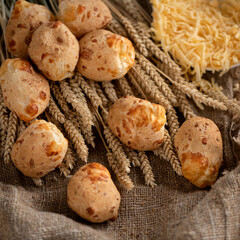 Freshly baked small buns. Scones with cheese. British cuisine. Background of sackcloth and ears of wheat. Soft focus.