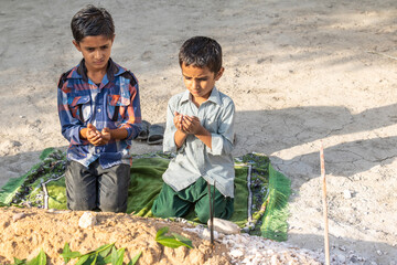 sad orphan children praying at their mother's grave