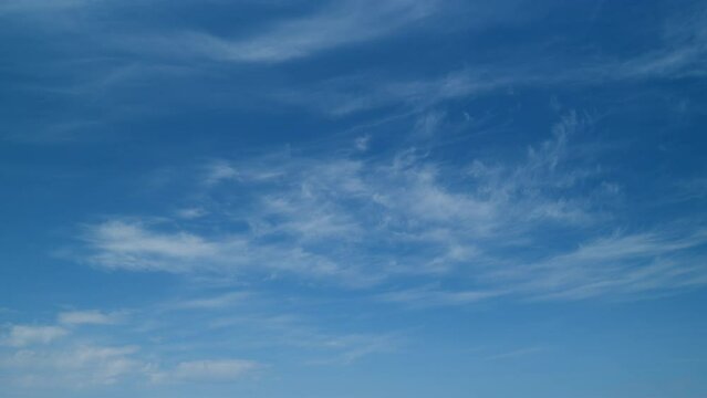 Clear blue sky with white wispy smoke cirrus clouds. Blue sky background with tiny cirrus clouds. Timelapse.
