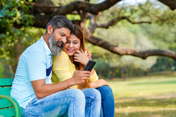 Indian man and woman watching some detail in smartphone at park.