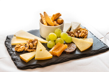 Platter of cheese, cracker, nuts and grapes served on cheeseboard