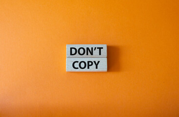 Don't copy symbol. Wooden blocks with words Don't copy. Beautiful orange background. Business and Don't copy concept. Copy space.