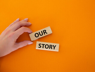 Our story symbol. Wooden blocks with words Our story Beautiful orange background. Businessman hand....