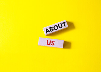About us symbol. Wooden blocks with words About us. Beautiful yellow background. Business and About us concept. Copy space.