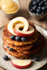 Frische Kartoffelpuffer / Reibekuchen mit Apfelmus und Heidelbeeren in kontrastreichem Umgebungslicht.