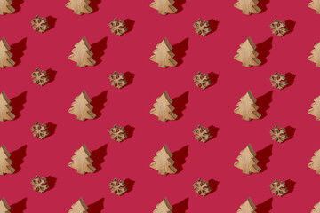 Christmas seamless pattern made from wooden toys on trendy color of 2023 year crimson red background. Minimal New Year celebration concept. Flat lay.