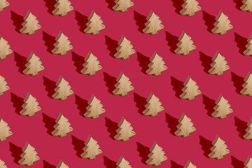 Christmas seamless pattern made from wooden tree toys on trendy color of 2023 year crimson red background. Minimal New Year celebration concept. Flat lay.
