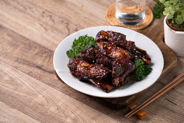 Barbecue pork spare ribs in a plate on wooden table background.