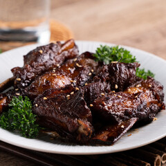 Barbecue pork spare ribs in a plate on wooden table background.