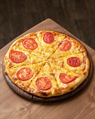Traditional Italian pizza Margarita with tomato and cheese on a wooden table. Vegetarian dish. Mediterranean Kitchen. Dark background. Top view, soft focus. 