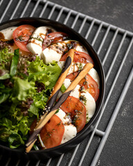 Caprese salad of tomatoes, mozzarella, sauce and lettuce. Italian food. Soft focus. Top view. Vegetarian food, healthy nutrition. Dark background. Close-up. View from above.