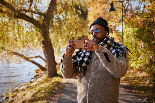 Man Taking Photos In Autumn Park