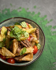 Roasted meat with potatoes, vegetables and parsley. A portion of the dish in a plate close-up. View from above. Soft focus. Copy space. 
