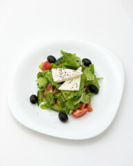 Fresh vegetable salad with feta cheese. Salt Greek. Vegetarian dish. Healthy food. Fitness menu. Salad on white plate on white background. Isolate View from above. Copy space. High quality photo