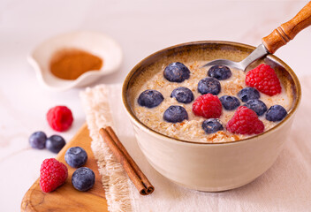 Plant based breakfast of steel cut oats with blueberries, raspberries, cinnamon and almond milk; copy space