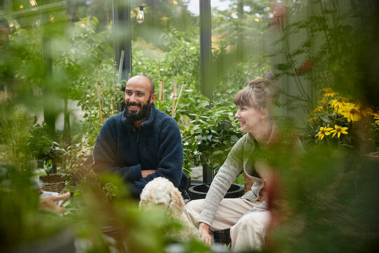 Smiling friends sitting in greenhouse