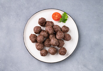 Fried meatballs on a white plate on a blue background. Meat meatballs cooked in the oven. The concept of healthy eating.