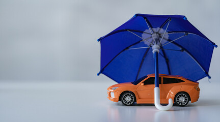 Businessman holding umbrella and close up toy car on table. Warranty. Repair. Finance. Banking and...
